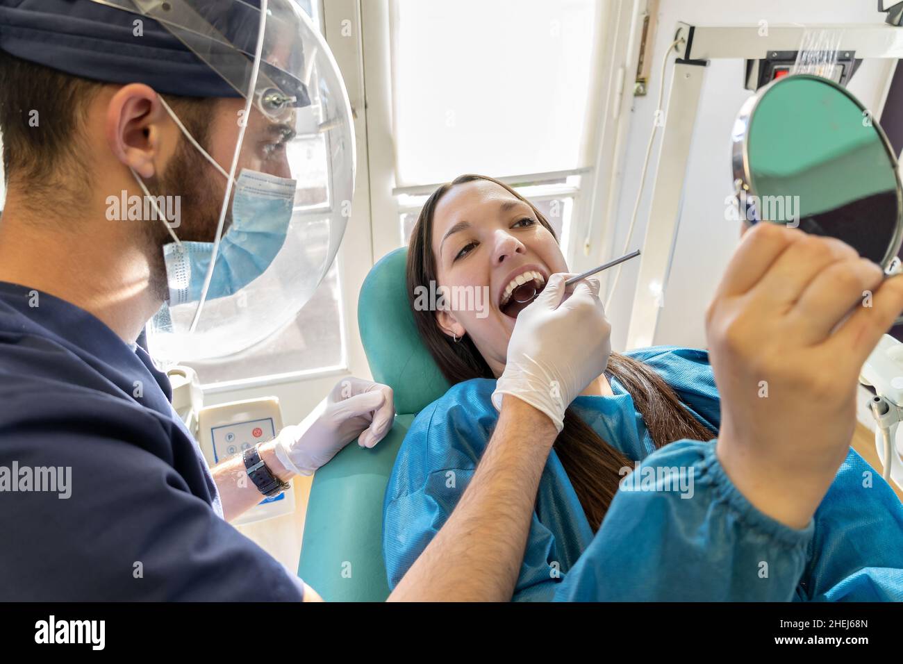 Young dentist in mask examining teeth of female Young dentist with mask and female patient in