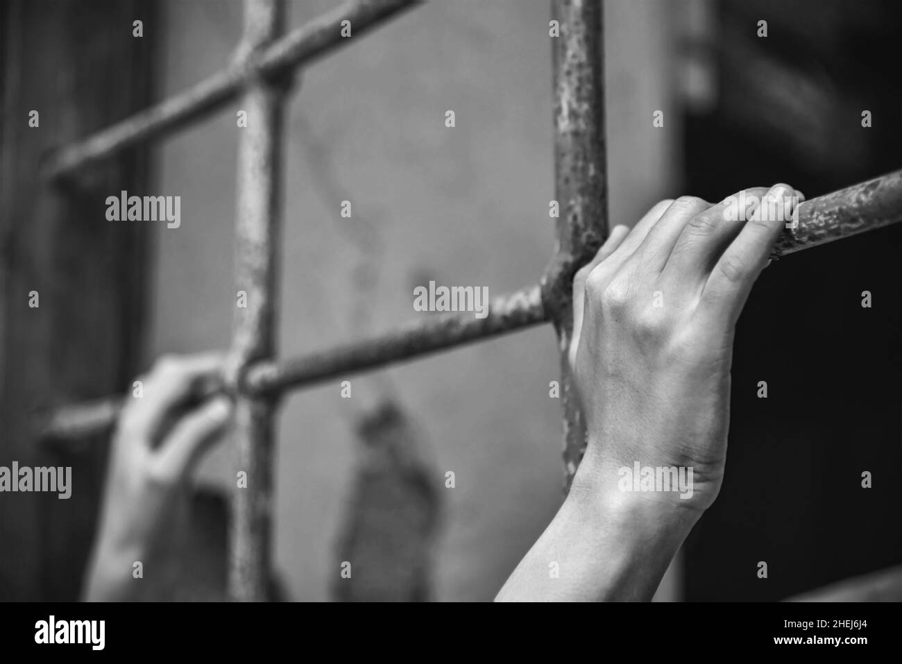 Hands of a young person holds ancient iron fencing, close up, black and white photography Stock Photo