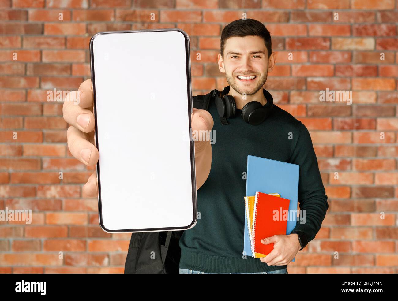 Learning App. Happy Male Student Demonstrating Big Blank Smartphone At Camera, Mockup Stock Photo