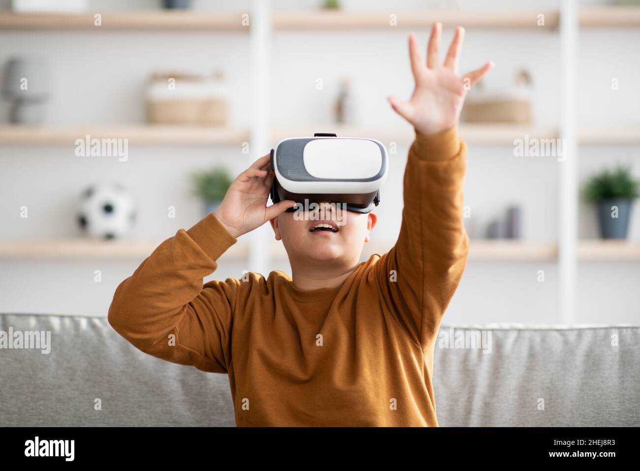 Excited kid using VR glasses, touching something invisible Stock Photo