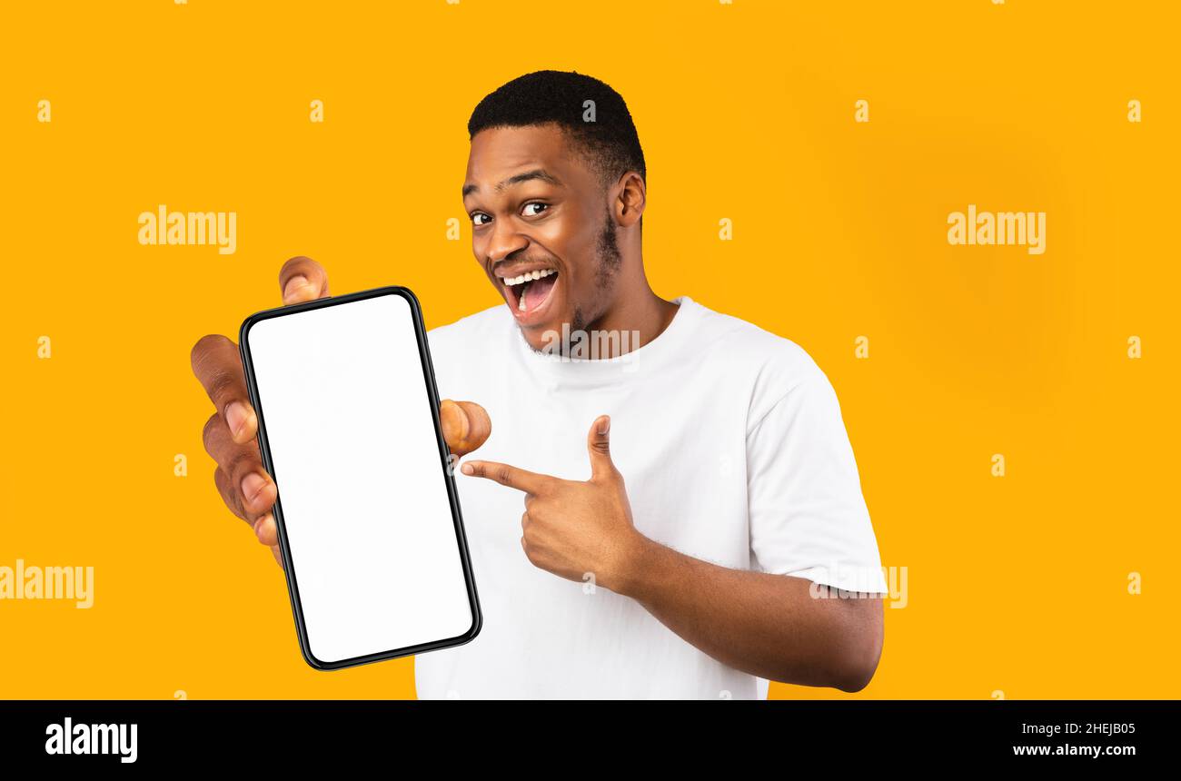 Happy handsome black man holding smartphone with empty screen Stock Photo