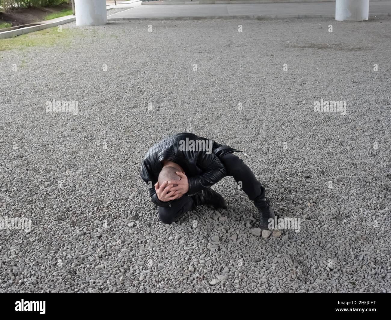 Bald man fell and holds his head after attack.  Stock Photo