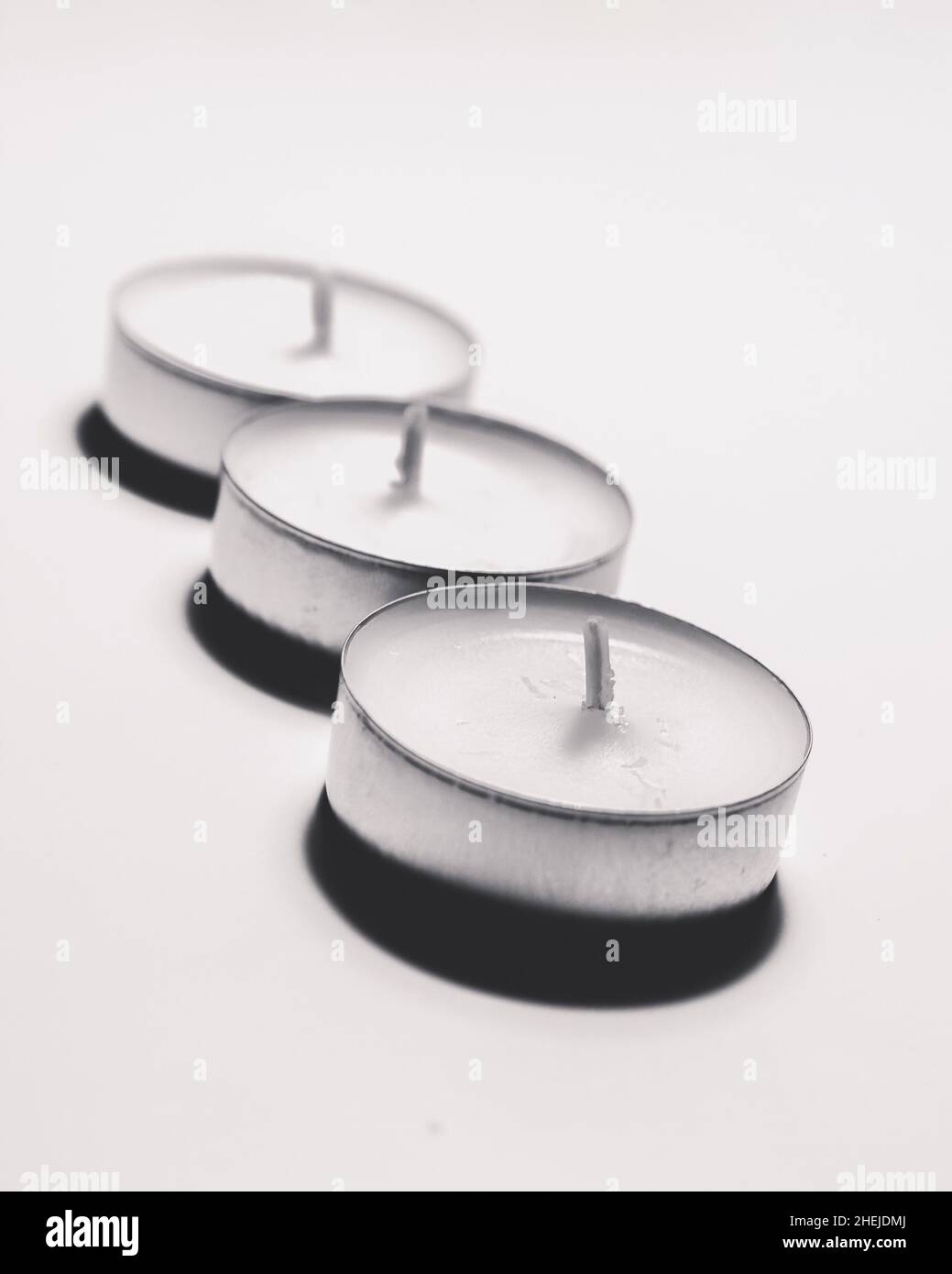Monochrome white three tea light on white background one after another Stock Photo