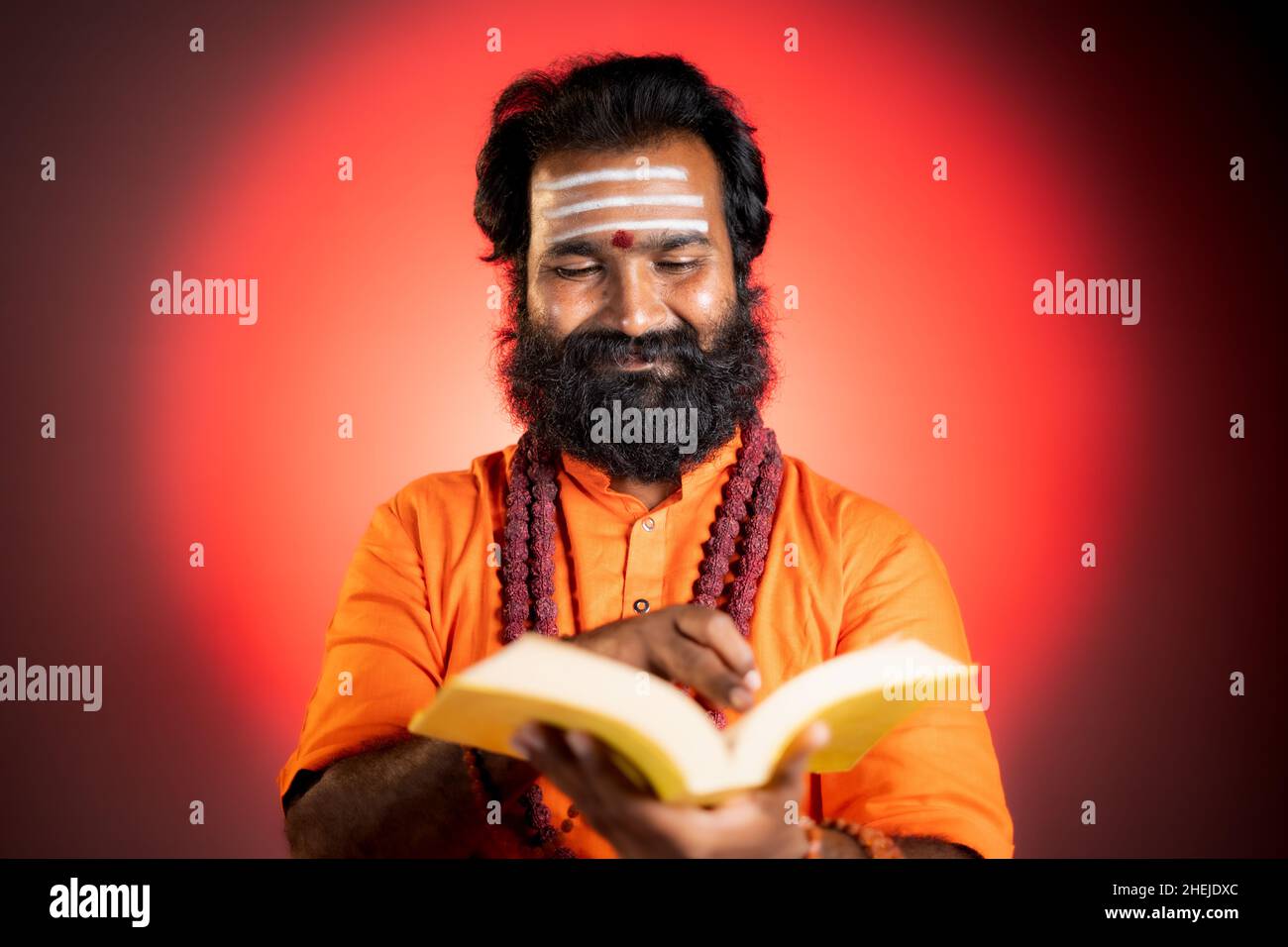 Focused holy saint reading astrology or holy vedas on studio background- concept of pandit studying religious Scripture and ramayana. Stock Photo