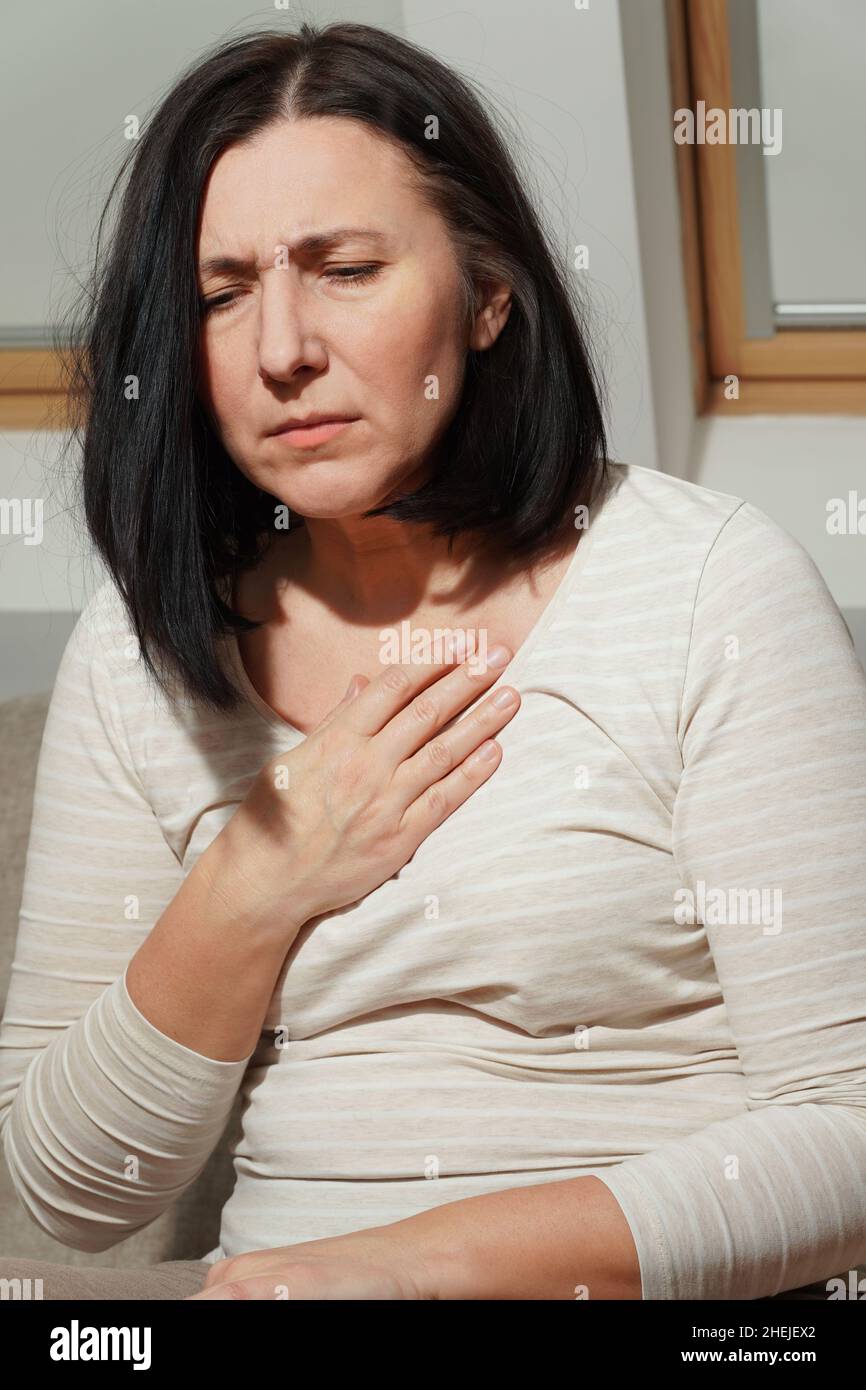 Middle aged mature woman having a heart attack. Woman suffering from chest pain. Health care and cardiological concept. Stock Photo