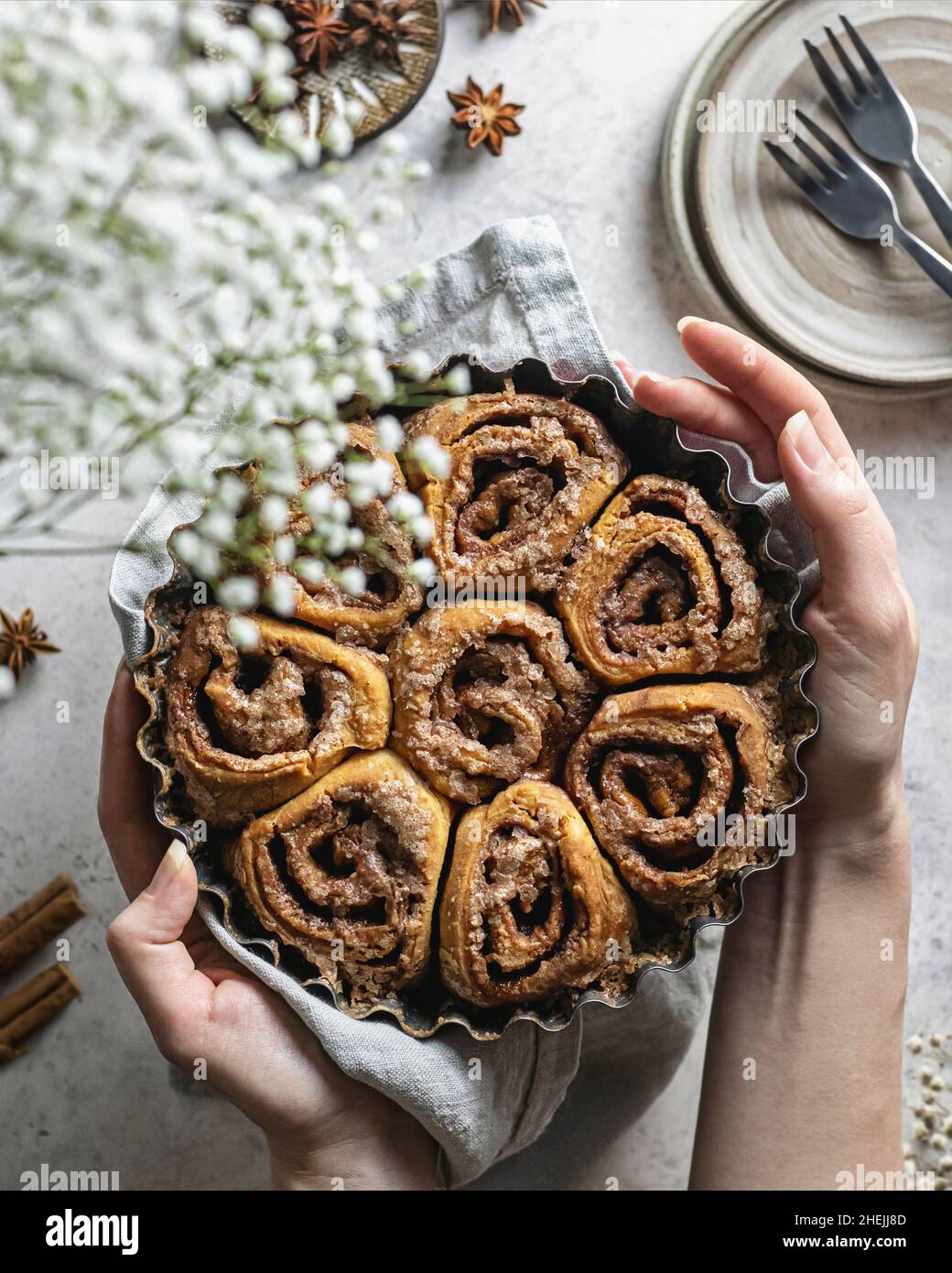Sinabon rolls on the baking form in the women's hands. Top view Stock Photo