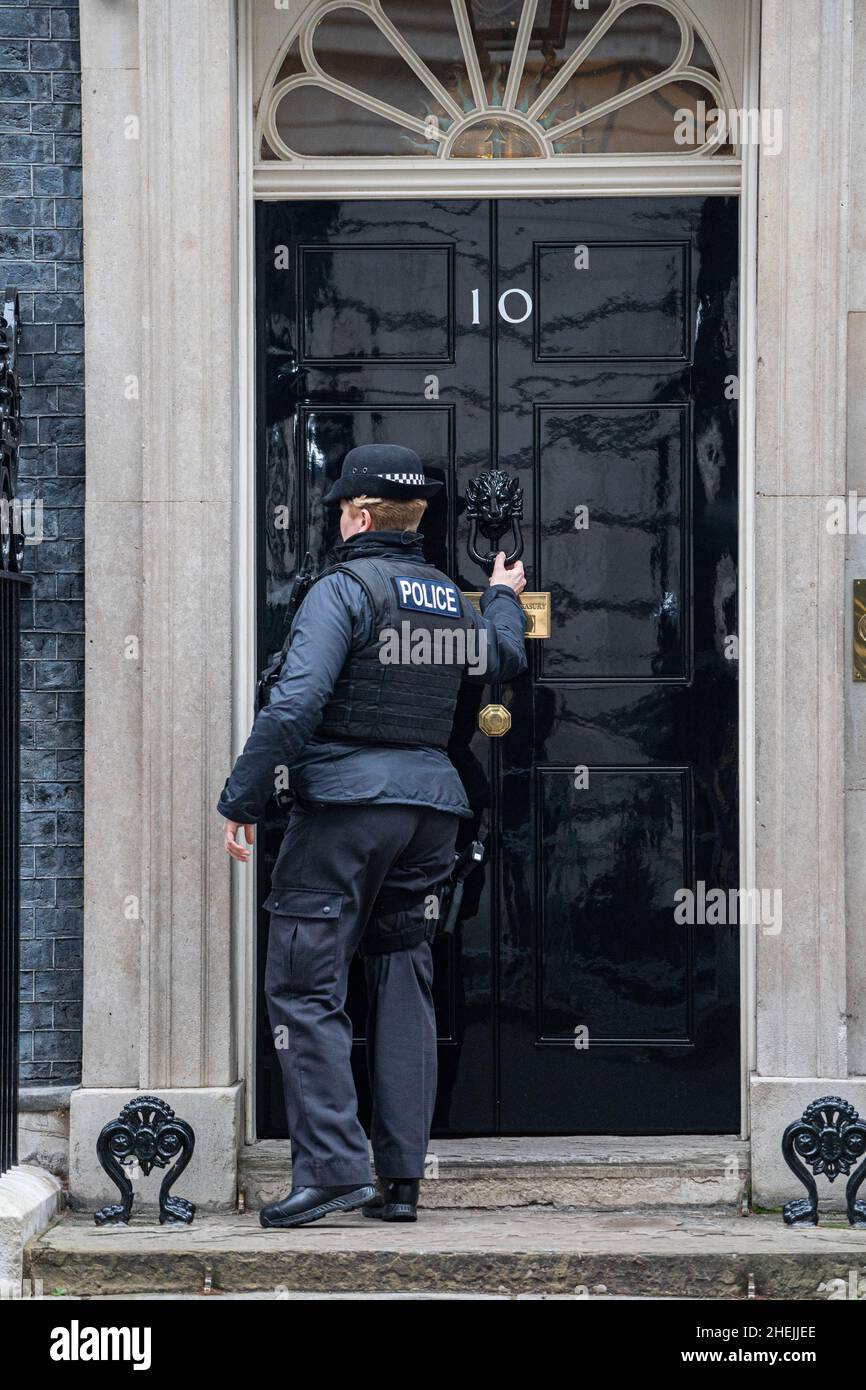 WESTMINSTER, LONDON,UK. 11 January 2022. A police officer knocks at the door of 10 Downing street. Prime Minister Boris Johnson is coming under pressure as the police consider conducting an investigation into a lockdown party which took place on 20 May 2020 when  it is alleged Downing street private secretary Martin  Reynolds invited more than 100 government employees to 'bring your own booze' at a garden party .Credit: amer ghazzal/Alamy Live News Stock Photo