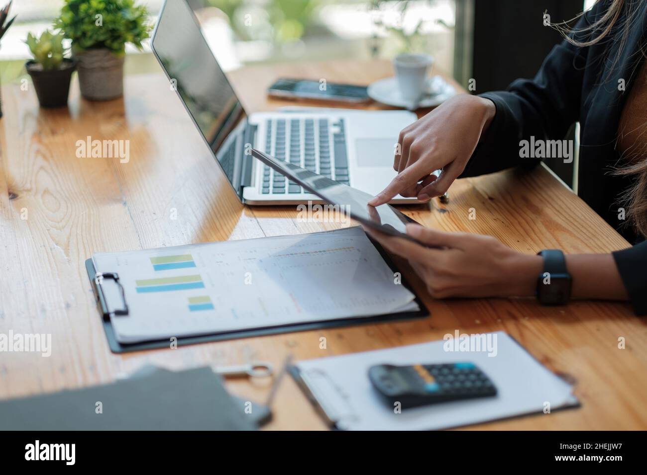 Close up business woman hands holds tablet pad while calculating charts