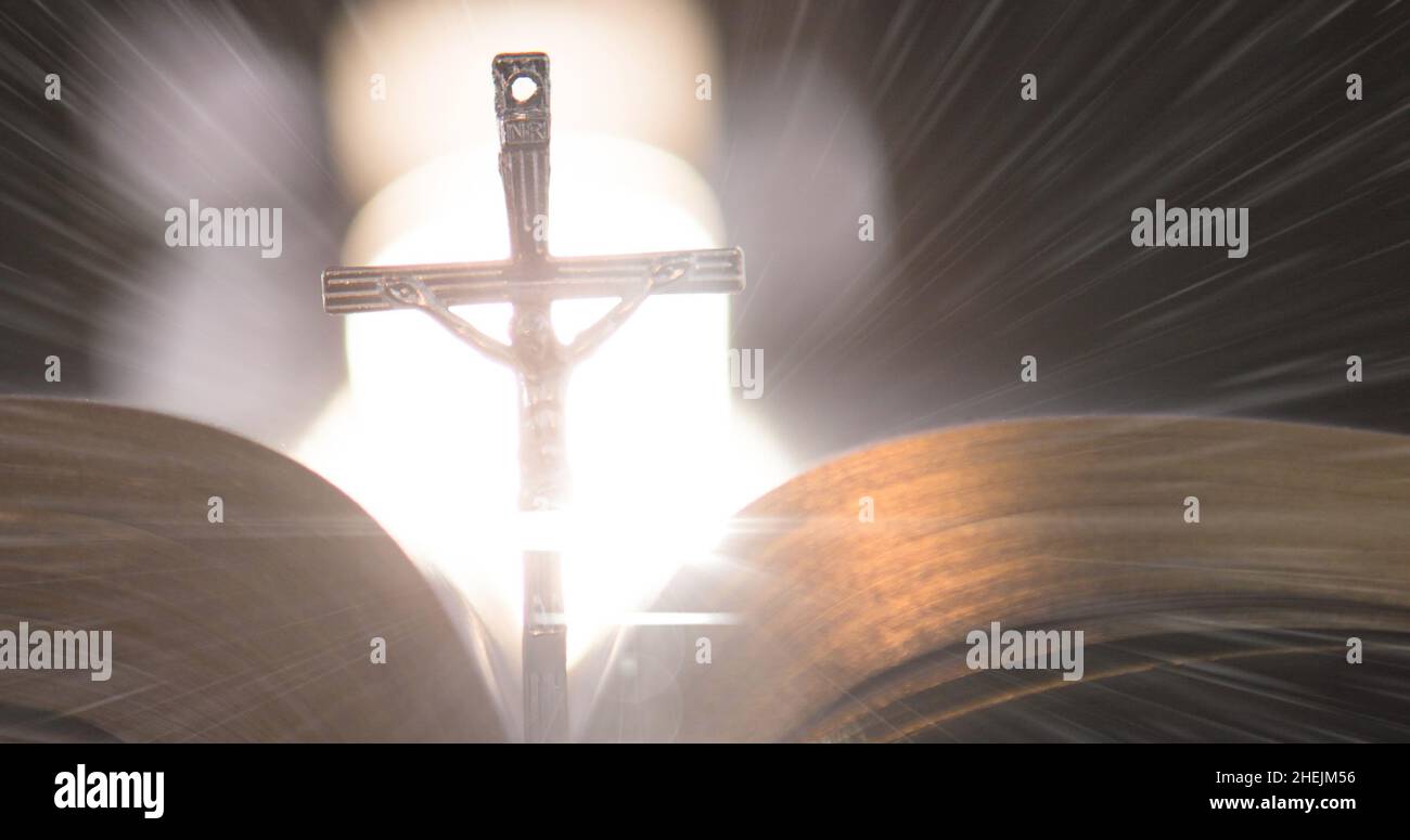 Image of christian cross with bible on glowing background Stock Photo