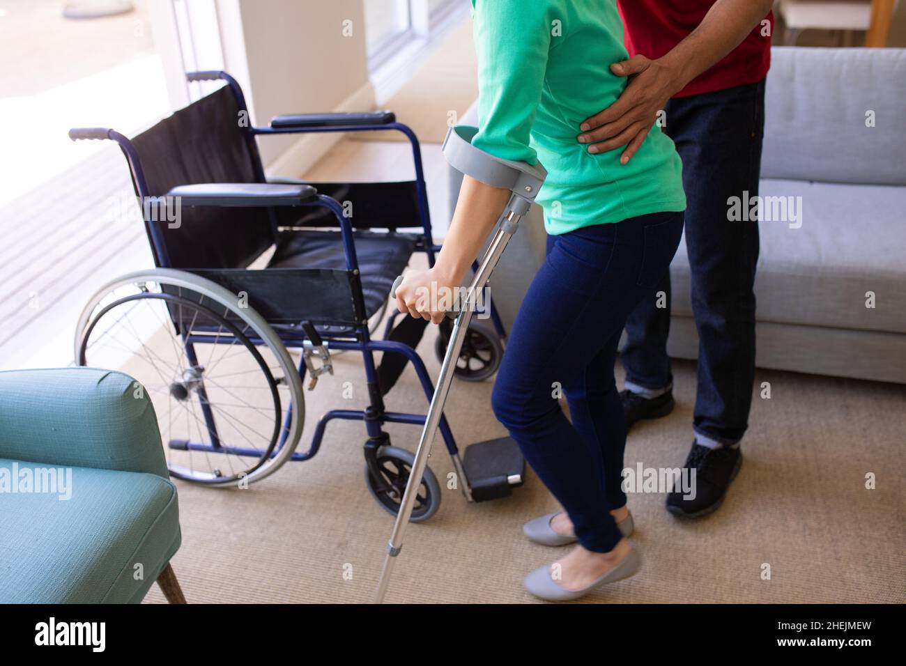 Mid section of african american man helping his disabled wife to walk with crutch at home Stock Photo
