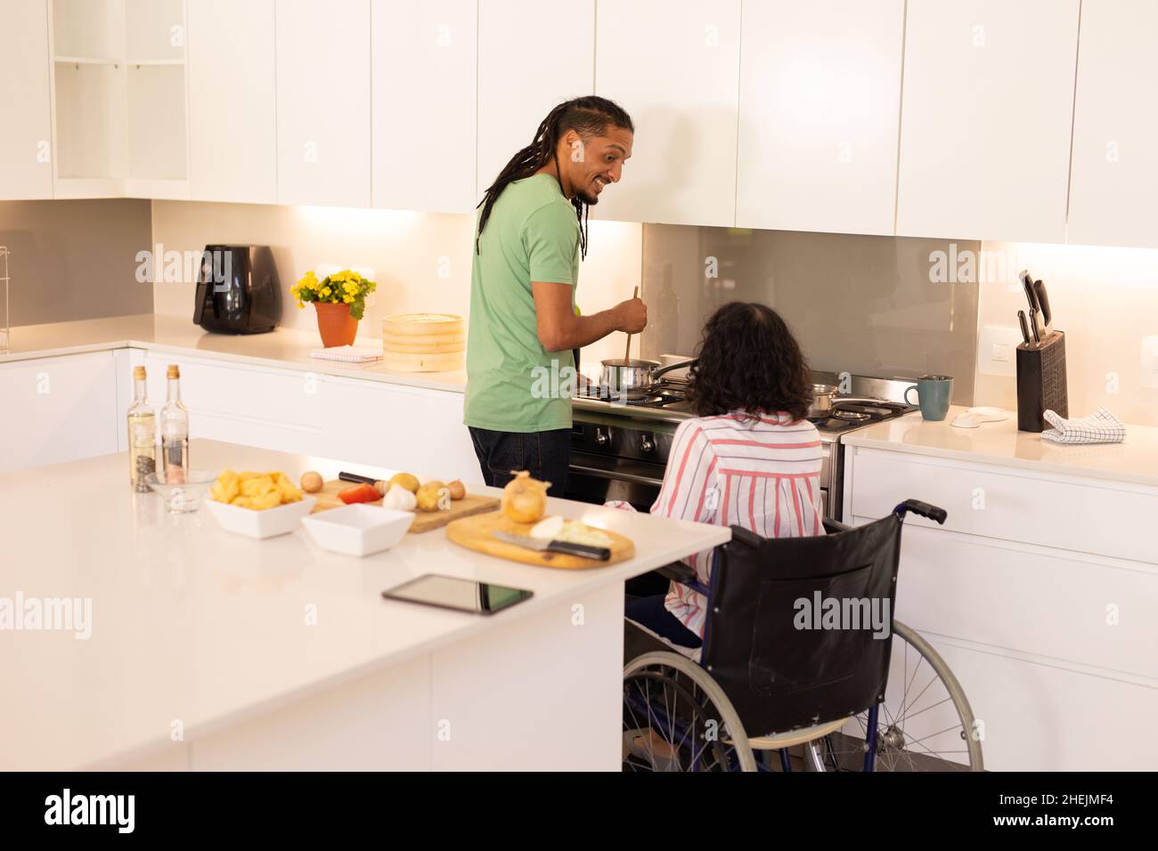 African american disabled woman on wheelchair and husband cooking in