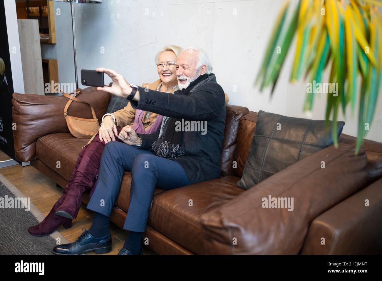 Elderly man photographing his wife and himself in a hotel lobby Stock Photo