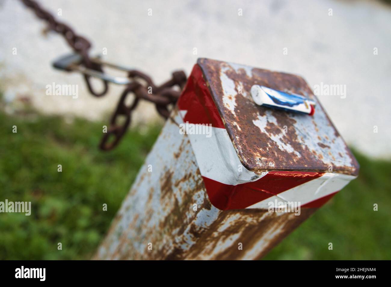 A rusty pole with chain to limit private property with a lighter left on it after it went out of gas Stock Photo