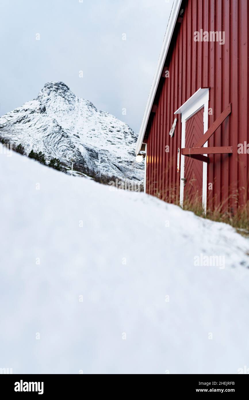 Red Rorbu fisherman cabin in deep snow in winter, Nusfjord, Nordland County, Lofoten Islands, Norway Stock Photo