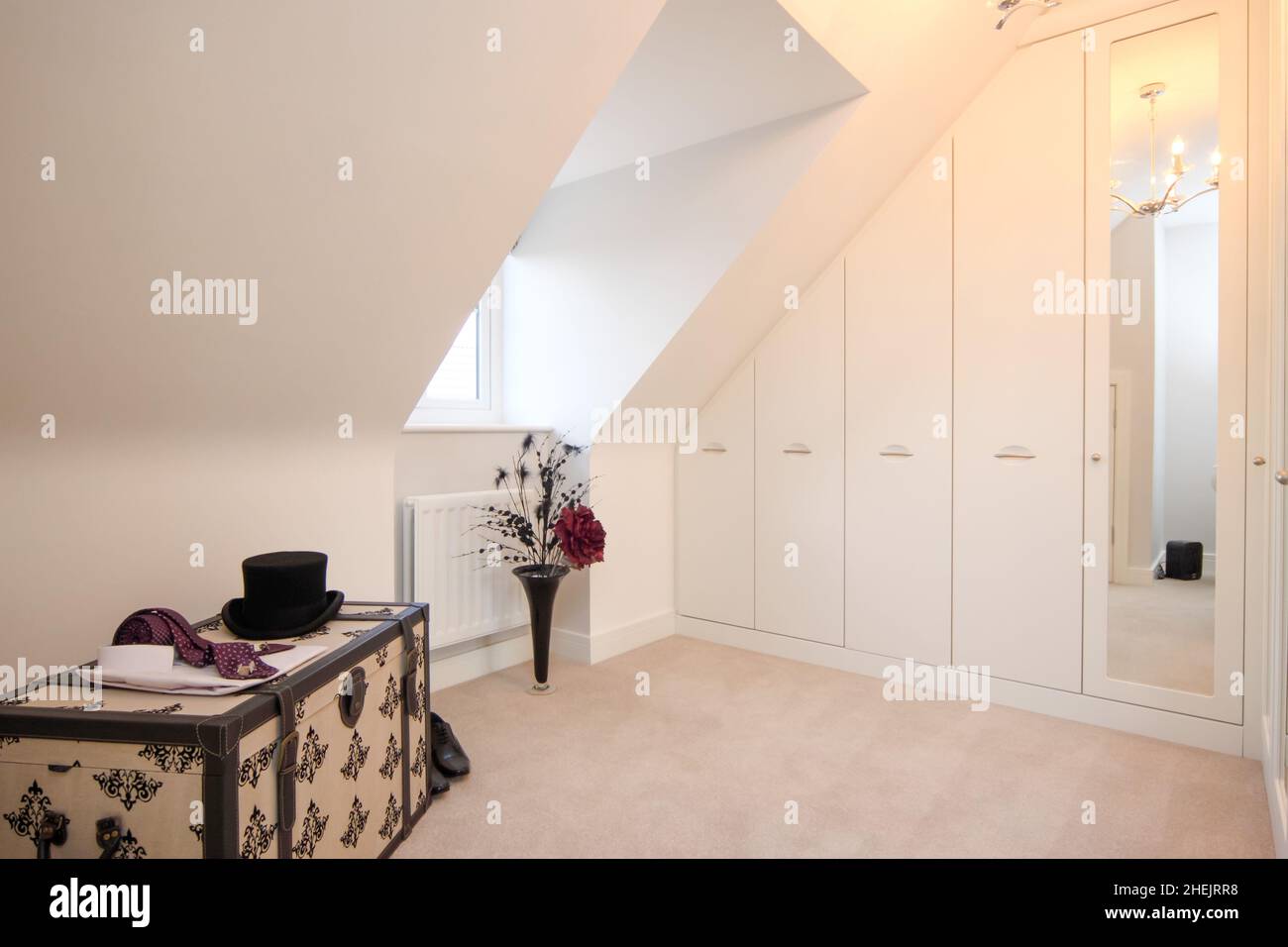 Changing room in modern new build house, trunk, wardrobes,top hat,dormer  window,flowers Stock Photo - Alamy