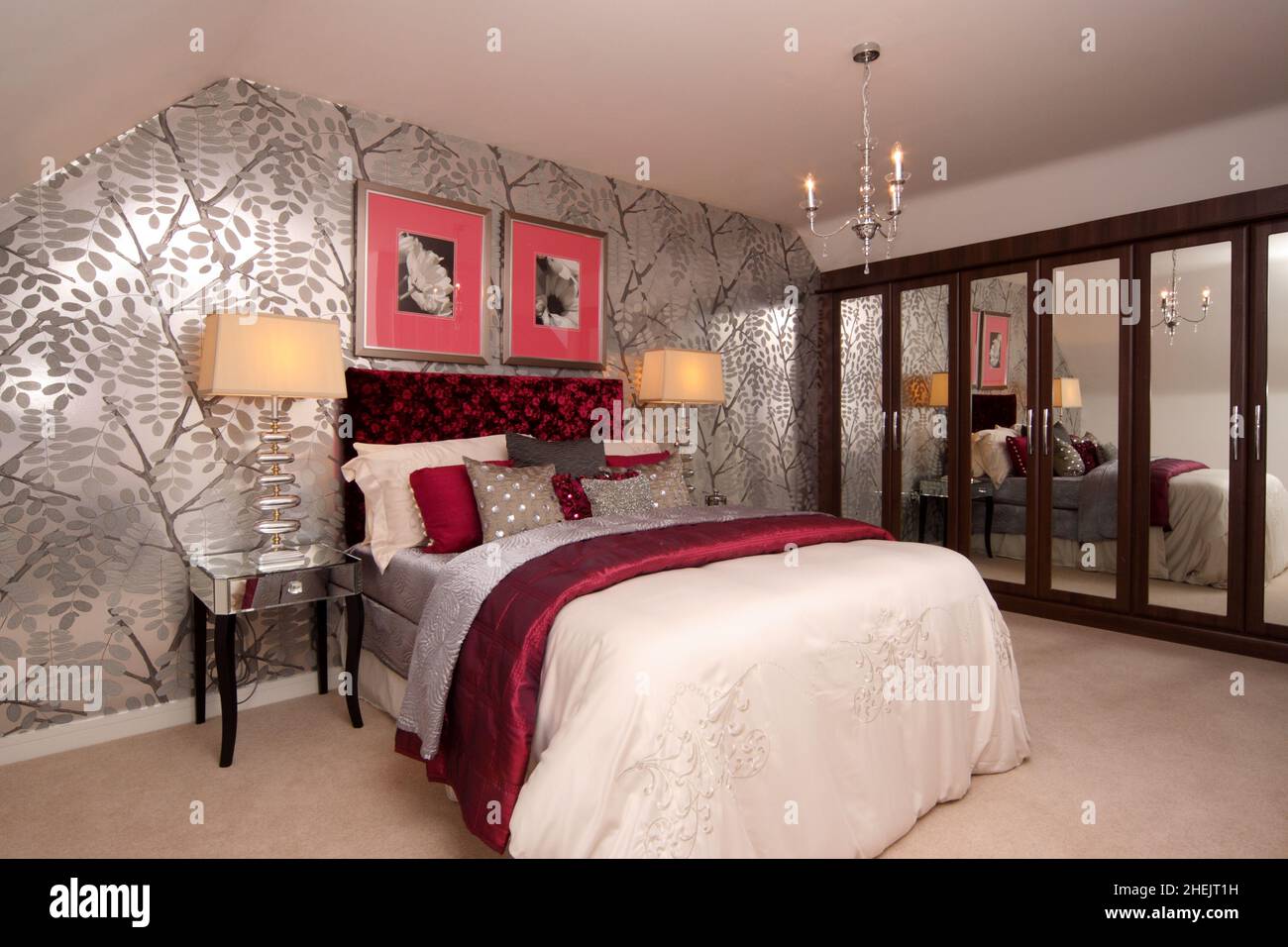 Double kingsize bed in bedroom of modern house, loft conversion,cream red silver theme,silver wallpaper,feature wall,bedside lights, fitted wardrobes, Stock Photo