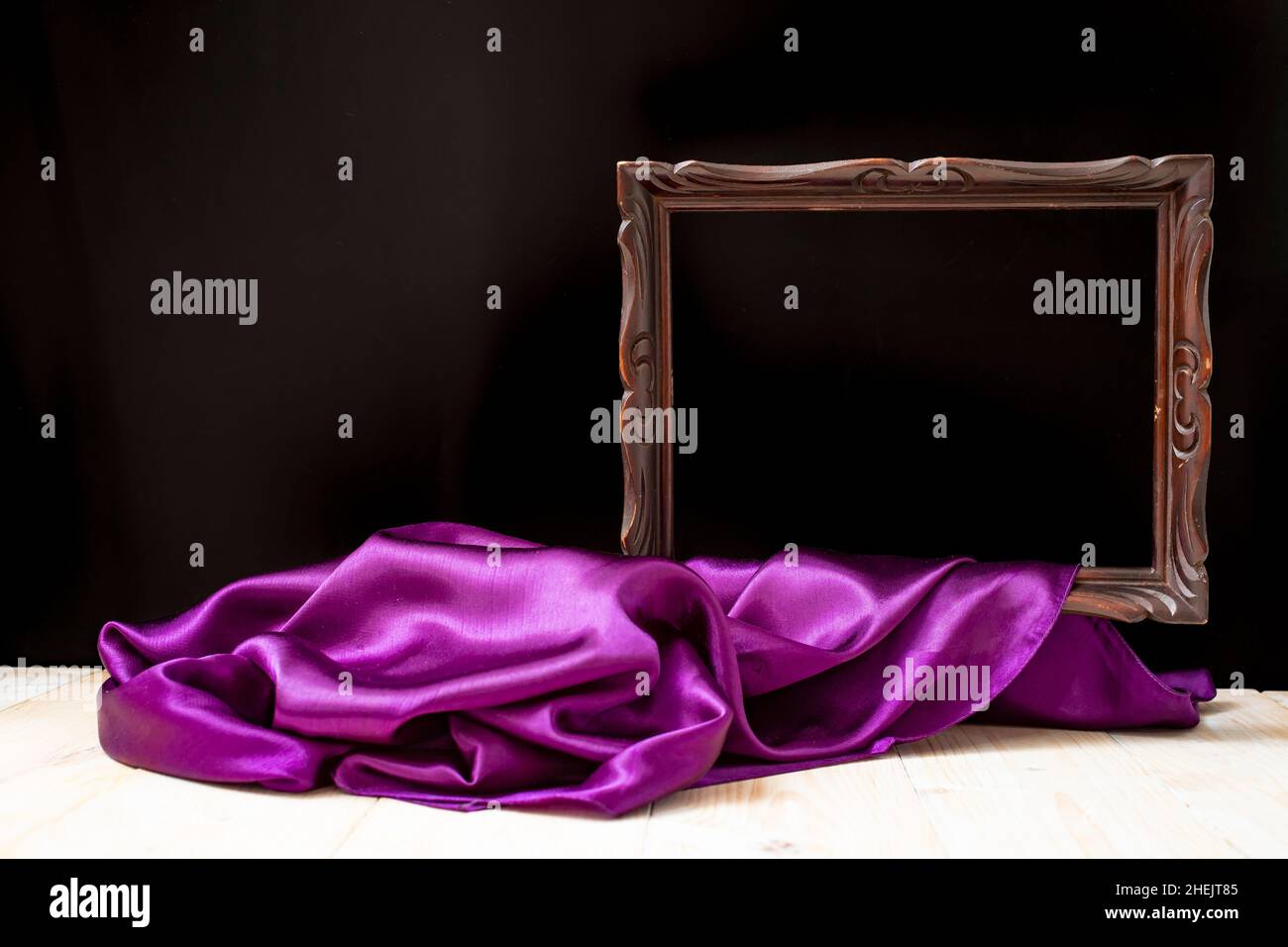 Brown wooden frame unveiled, and purple satin on black background, wallpaper design Stock Photo