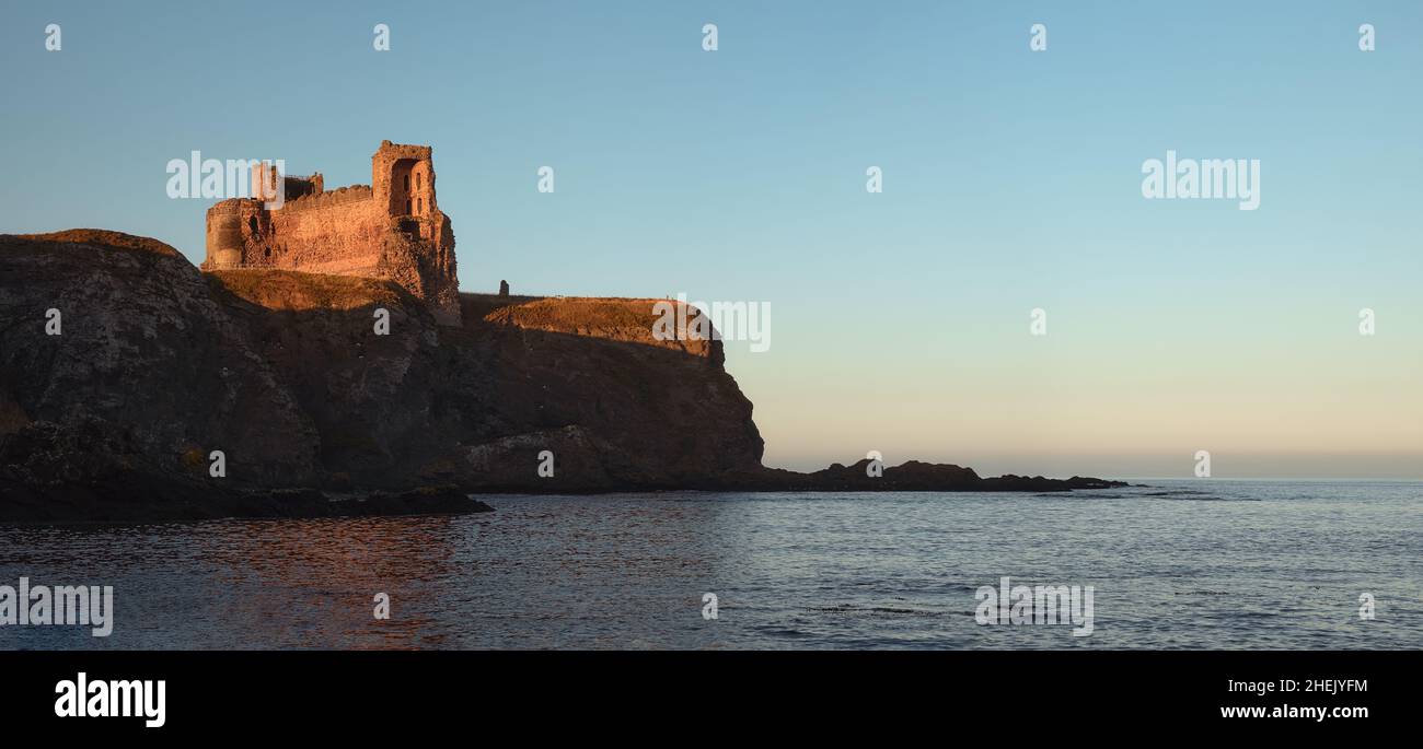 Ruins of an old castle standing on a cliff by the sea at sunset. Scotland  Stock Photo