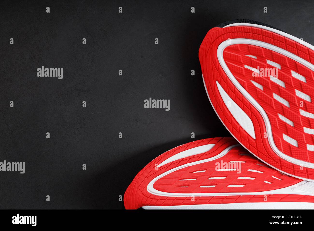 Running shoes with red soles on a black background. Closeup, top view