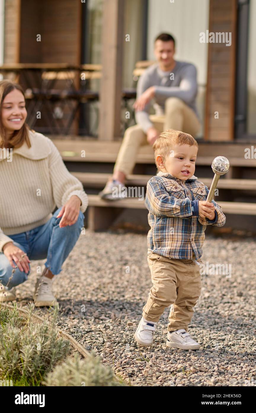 Child rejoicing at toy outdoors and parents watching Stock Photo