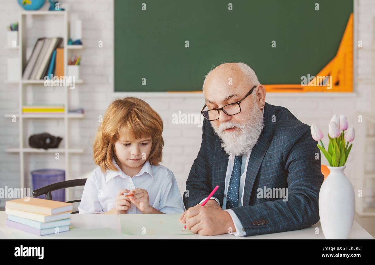 Mature grandfather helping to grandson with school assignment, older ...