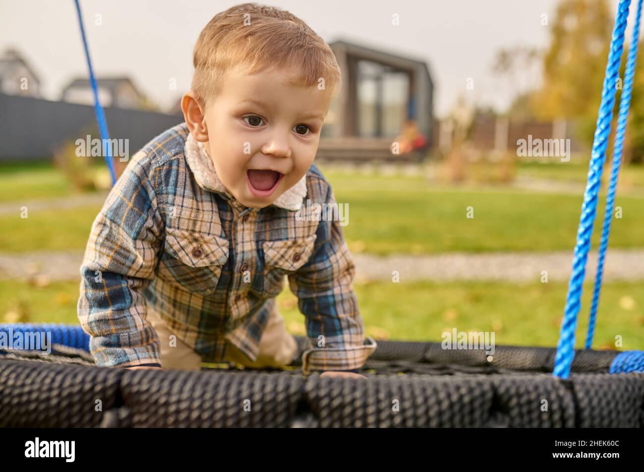 Child with open mouth on swing near country house Stock Photo