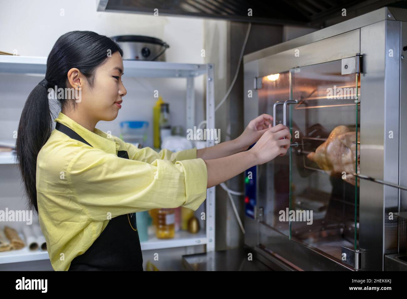 https://c8.alamy.com/comp/2HEK6KJ/young-asian-woman-working-in-the-kitchen-and-regulating-ovens-temperature-2HEK6KJ.jpg