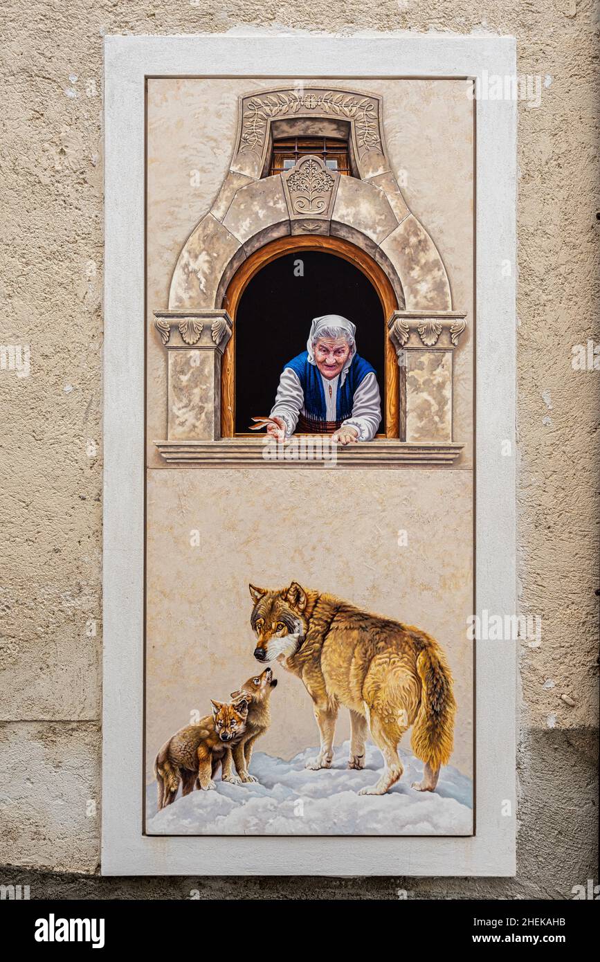 Particular window with an elderly lady looking out and a mural drawn with representations of wolves. Secinaro, province of L'Aquila, Abruzzo, Italy Stock Photo