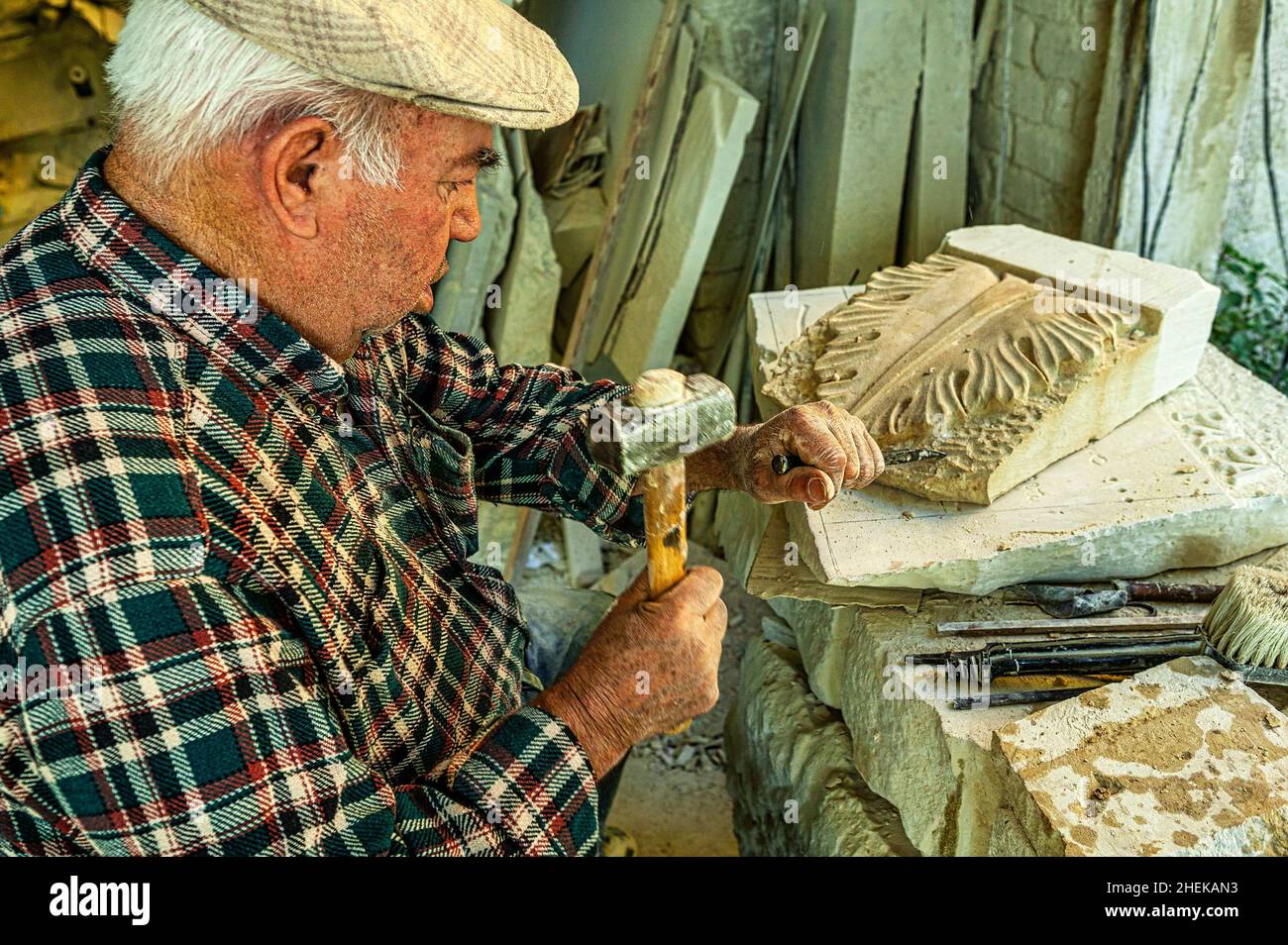 Stonemason at work on a stone sculpture. Creation of handcrafted decorations carved in the Maiella stone. Lettomanoppello, Pescara province, Abruzzo, Stock Photo