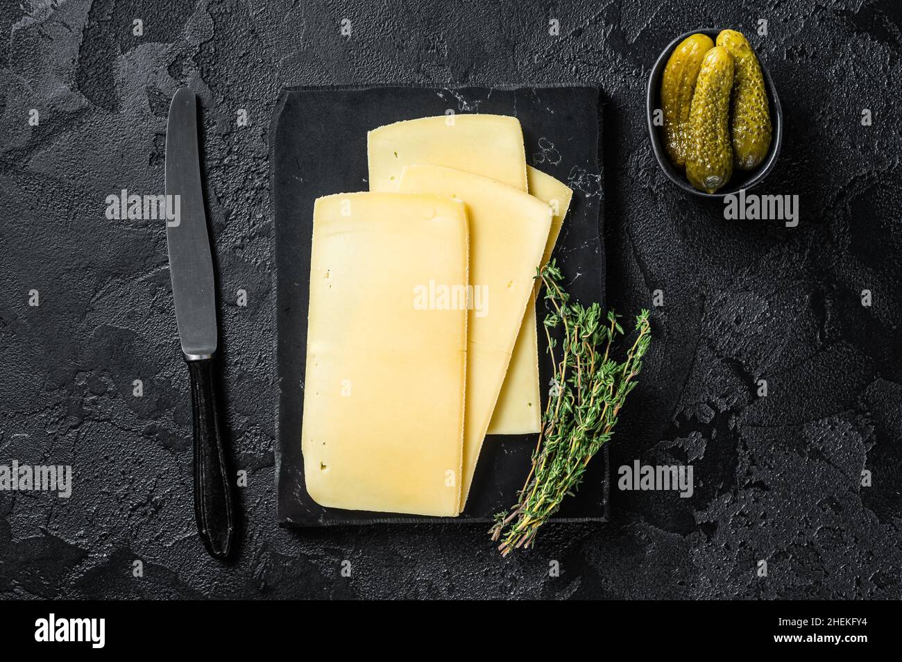 Fresh Uncooked Raclette Swiss cheese slices on marble board. Black ...