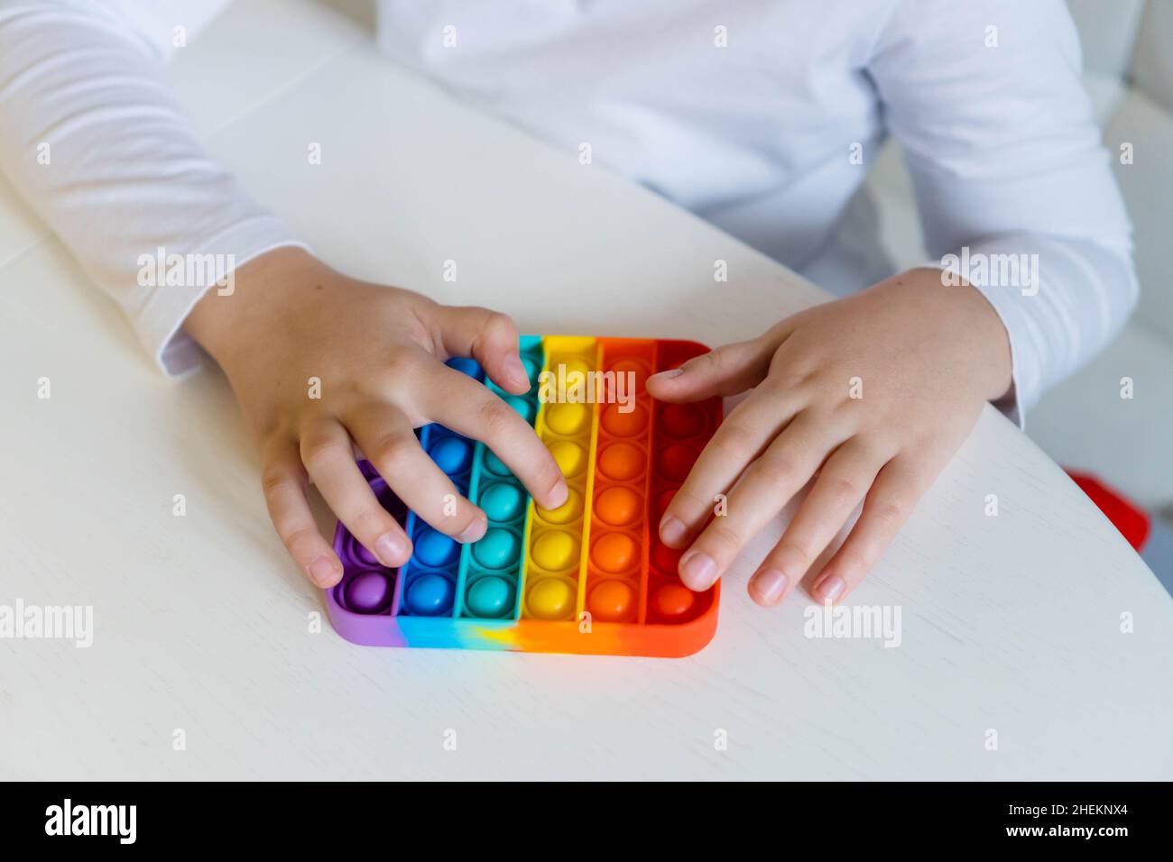 Girl hands close up playing with rainbow pop it fidget. The concept of