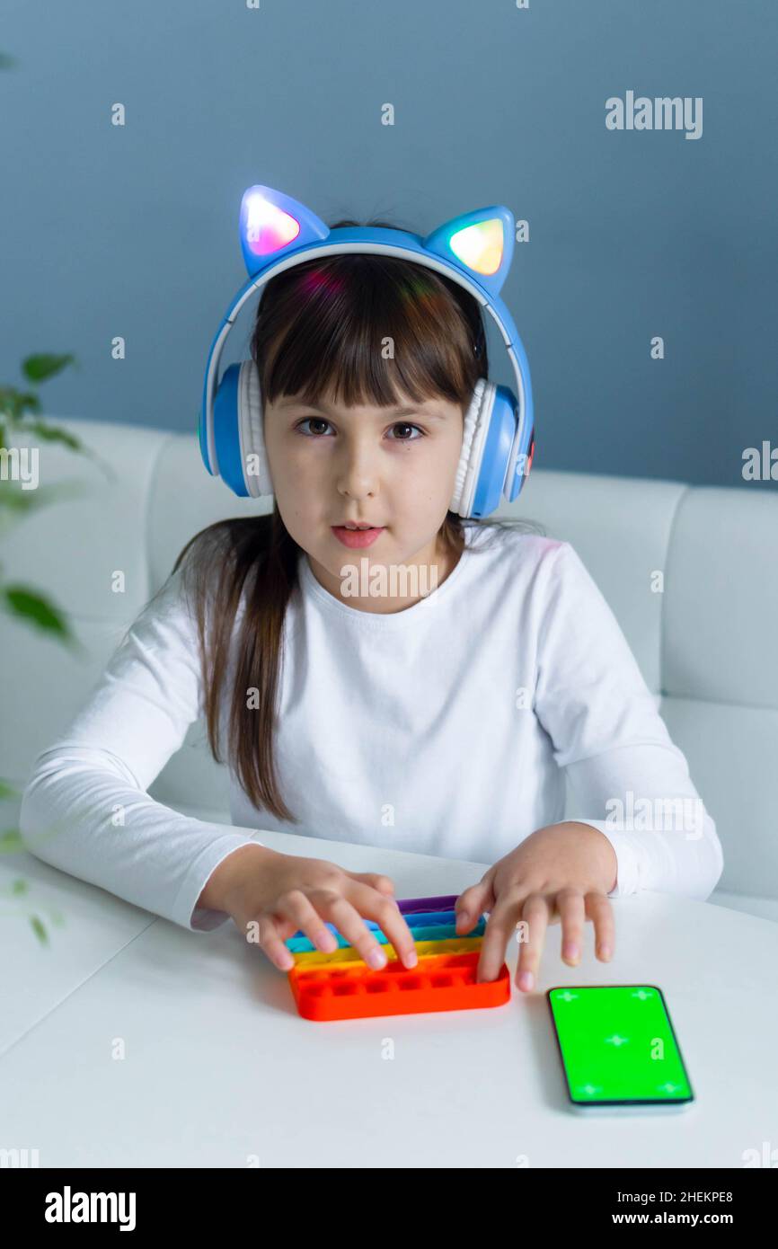 Girl with rainbow pop it fidget and using headphones and smartphone