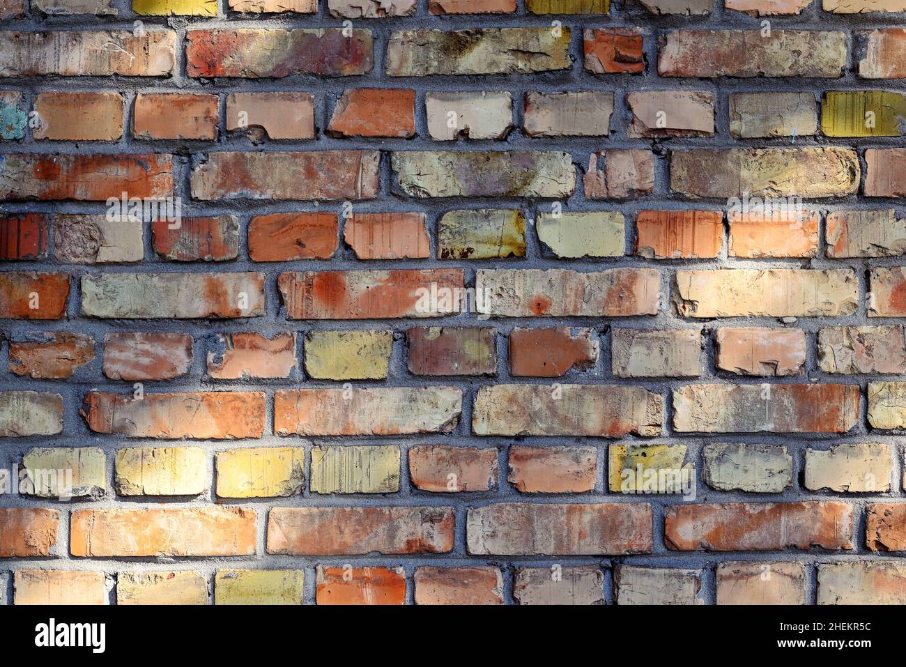 Abstract background. Texture of an old brick wall close-up. Orange, red, yellow bricks. Stock Photo