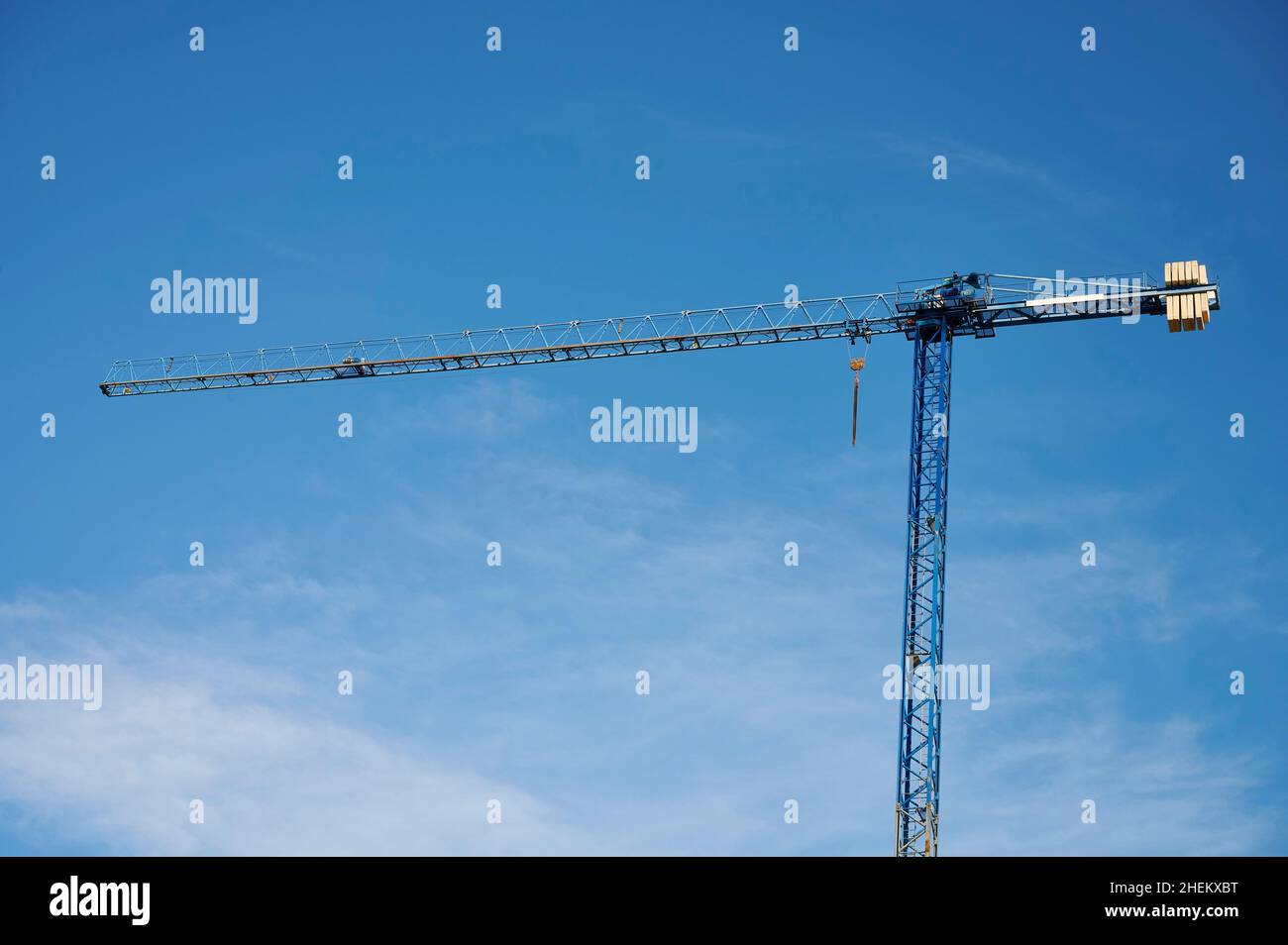 Construction cranes seen against a blue sky with clouds Stock Photo