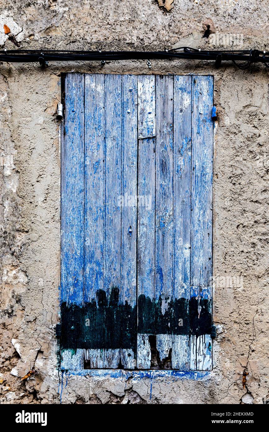 old rotten closed window with peeling white dirty paint as symbol for ...