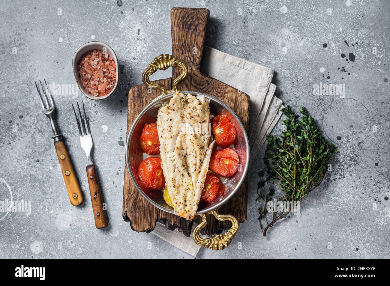 Roasted Haddock fish fillet in skillet with tomato and potato. Gray