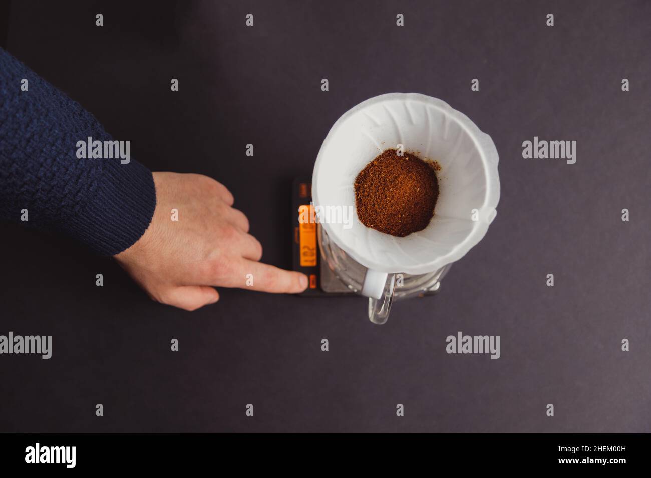 Man barista makes coffee, scaling ground coffee in paper filters using