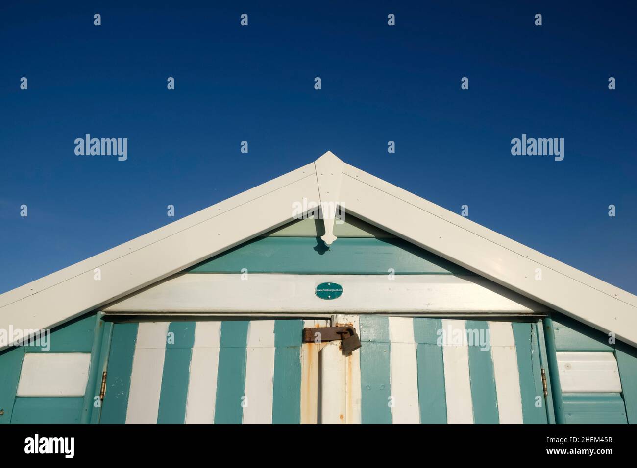 A Winters Day on the Promenade at Weston-super-Mare. Green striped beach hut blue sky, off season. Stock Photo