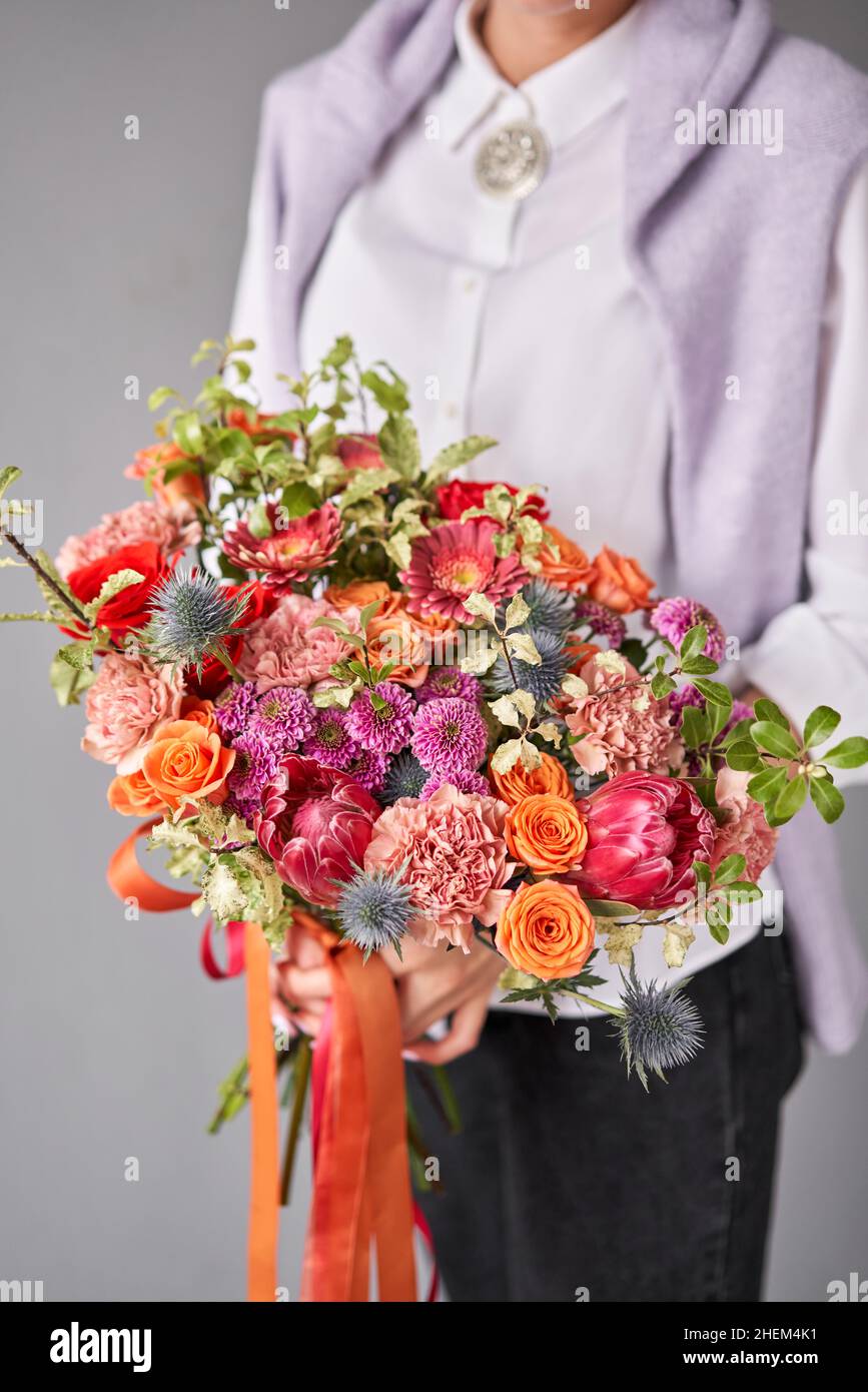 Flower arrangement in Wicker basket. Beautiful bouquet of mixed flowers in woman hand. Handsome fresh bouquet. Small flower shop and Flowers delivery Stock Photo