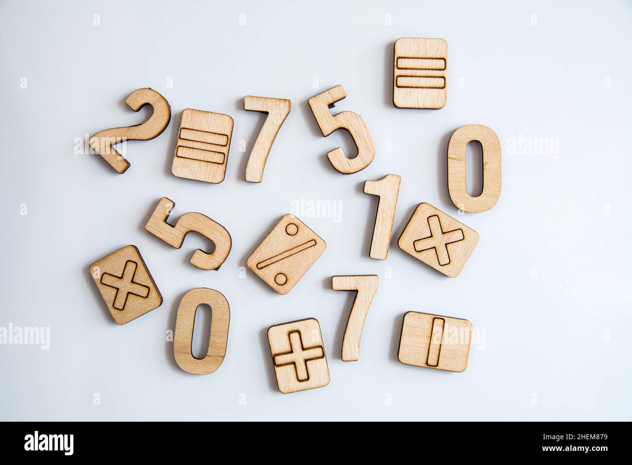 Wooden numbers symbols on white background. Randomly arranged numbers and arithmetic symbols. Different wooden digits and arithmetic symbols. Stock Photo