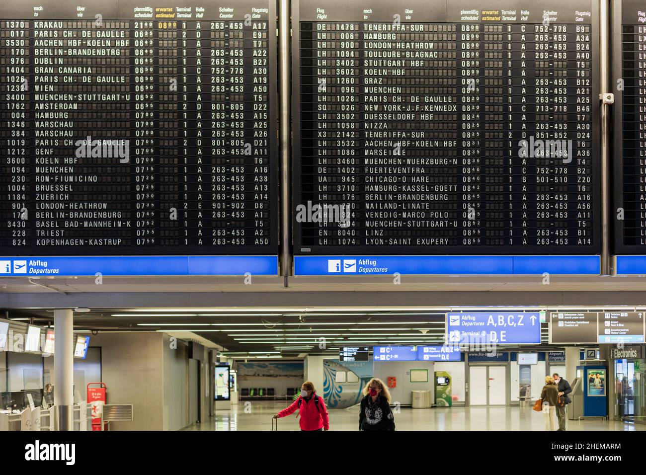 FRANKFURT, GERMANY NOVEMBER 11, 2021 Two women in medical face masks walk with suitcases at