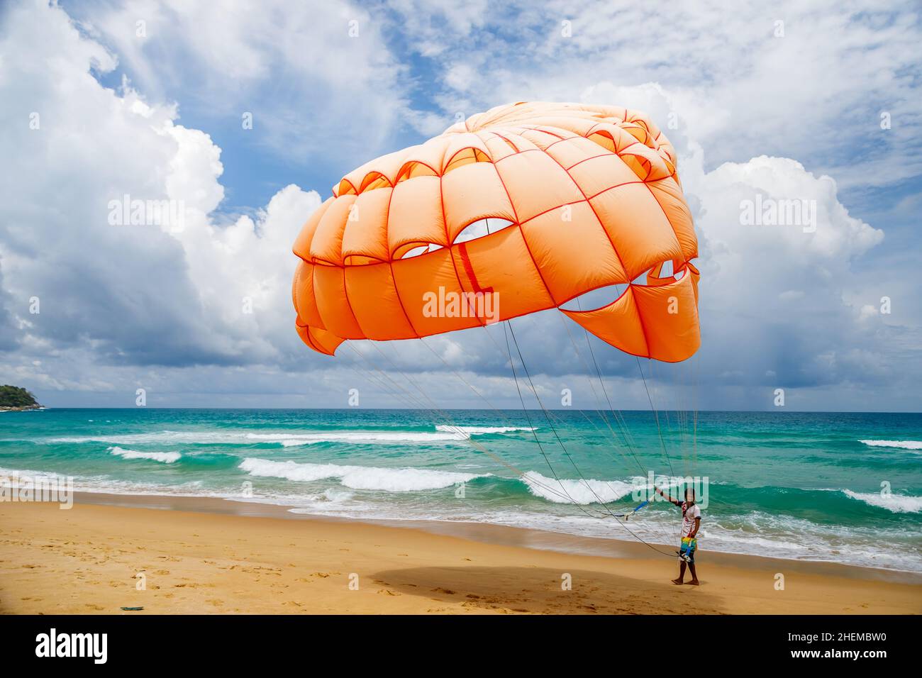 Opened orange parachute on the beach in Thailand. The man offers to ...
