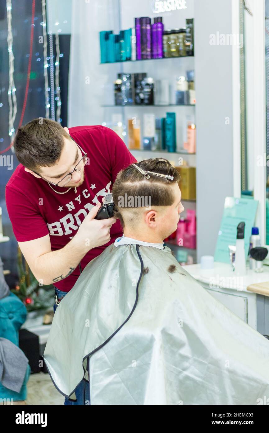 A male hairdresser makes a haircut for a client with a hair clipper and comb. The man got his hair cut at the barbershop. Russia Moscow 17 November 20 Stock Photo