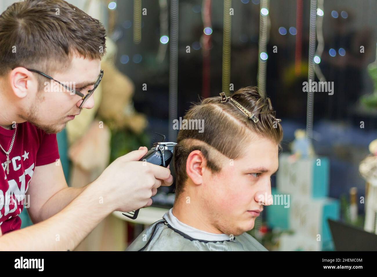 A male hairdresser makes a haircut for a client with a hair clipper and comb. The man got his hair cut at the barbershop. Russia Moscow 17 November 20 Stock Photo