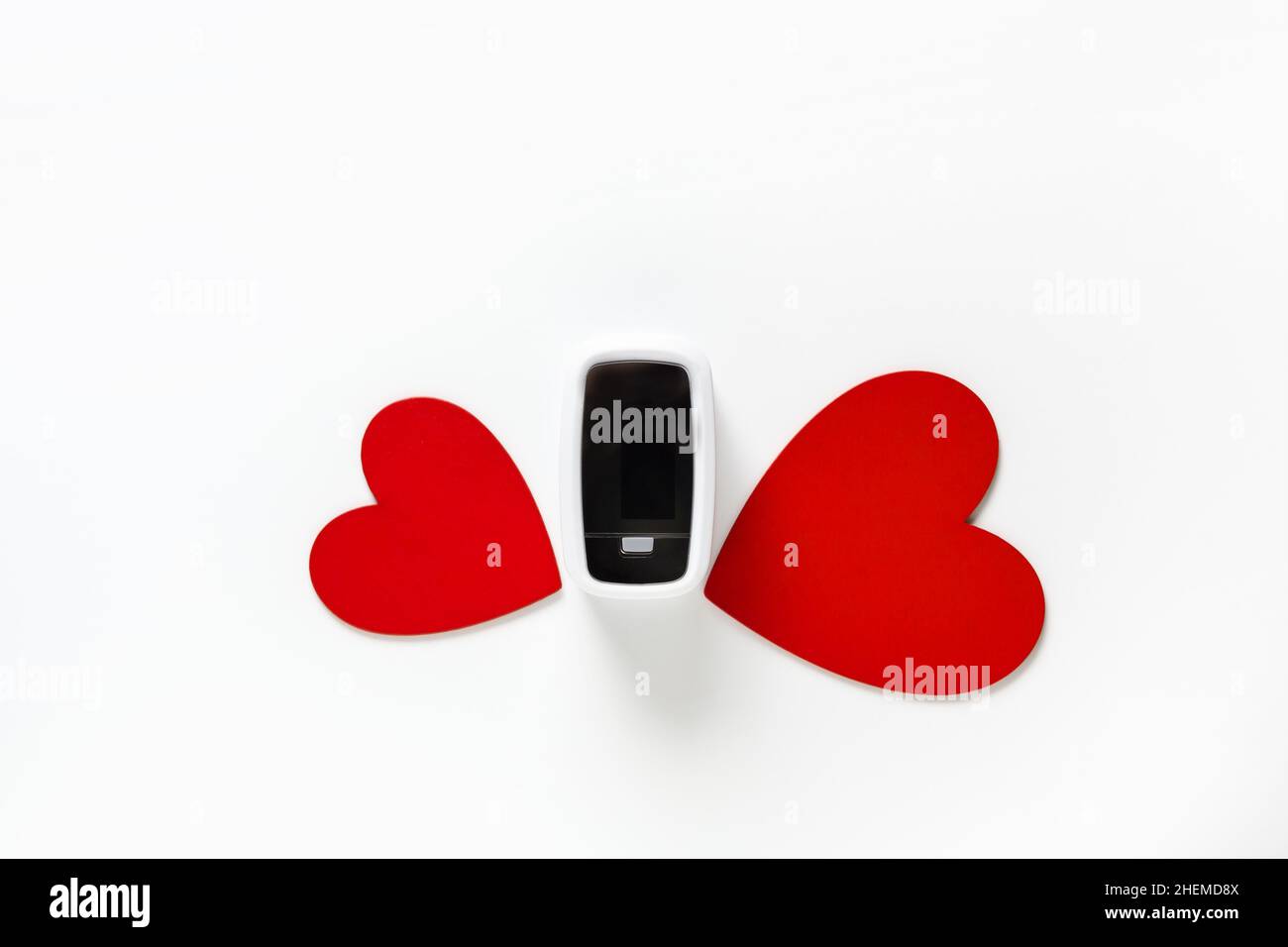 Covid Valentine day gift concept, pulse oximeter among flower from red hearts on white background top view Stock Photo