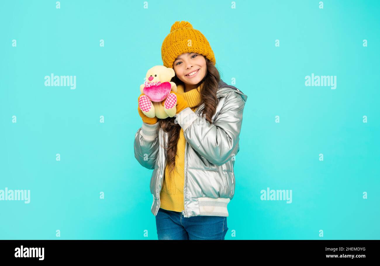 cheerful teen girl in winter clothes hold toy on blue background, valentines day Stock Photo