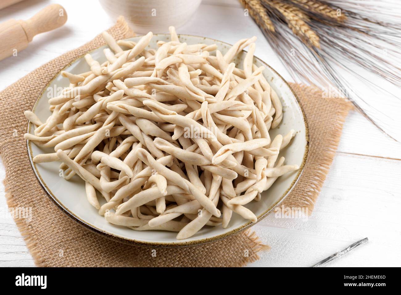 Whole grain wheat raw apulian pasta called Pizzarieddi or maccaruni on a  ceramic plate on white wooden table. Fresh maccheroni typical dish of Puglia  Stock Photo - Alamy