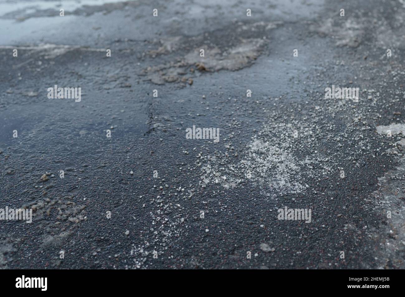 Deicing chemical reagent on road in winter time. Pavement is sprinkled with technical salt