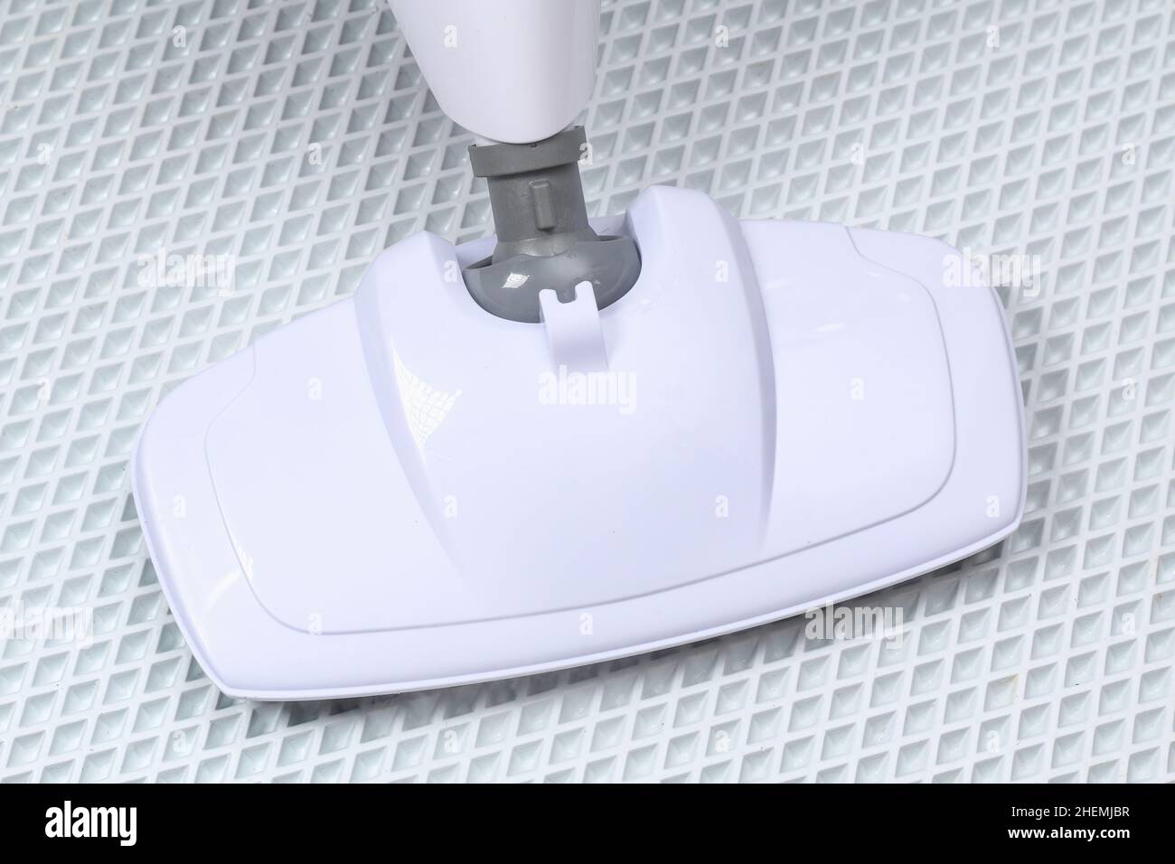 A man washes a white rug with a steam mop. Killing germs