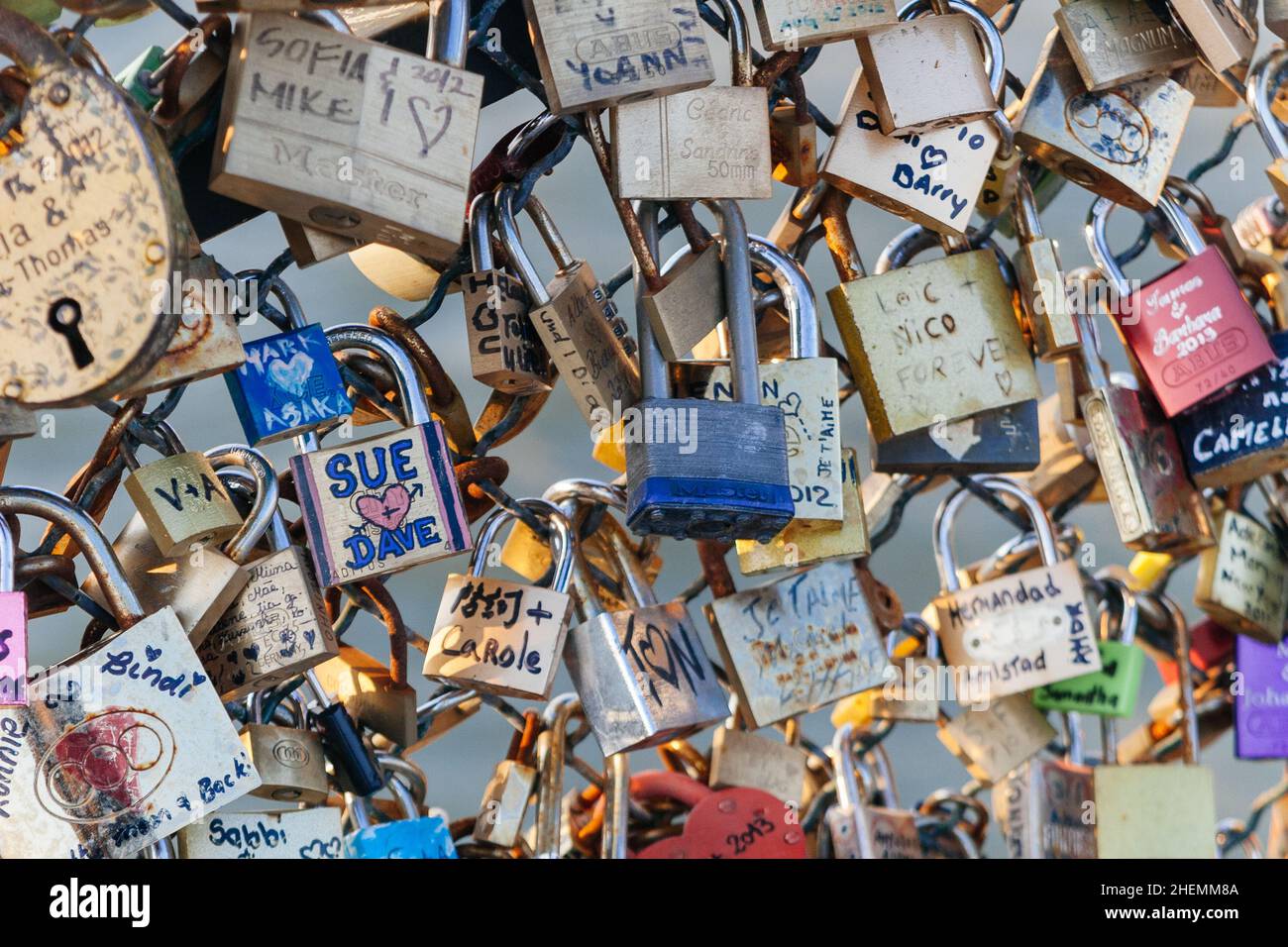 Padlocks with couples names on declaring everlasting love, locked onto the mesh fence of Post des Arts in Paris, France. Stock Photo